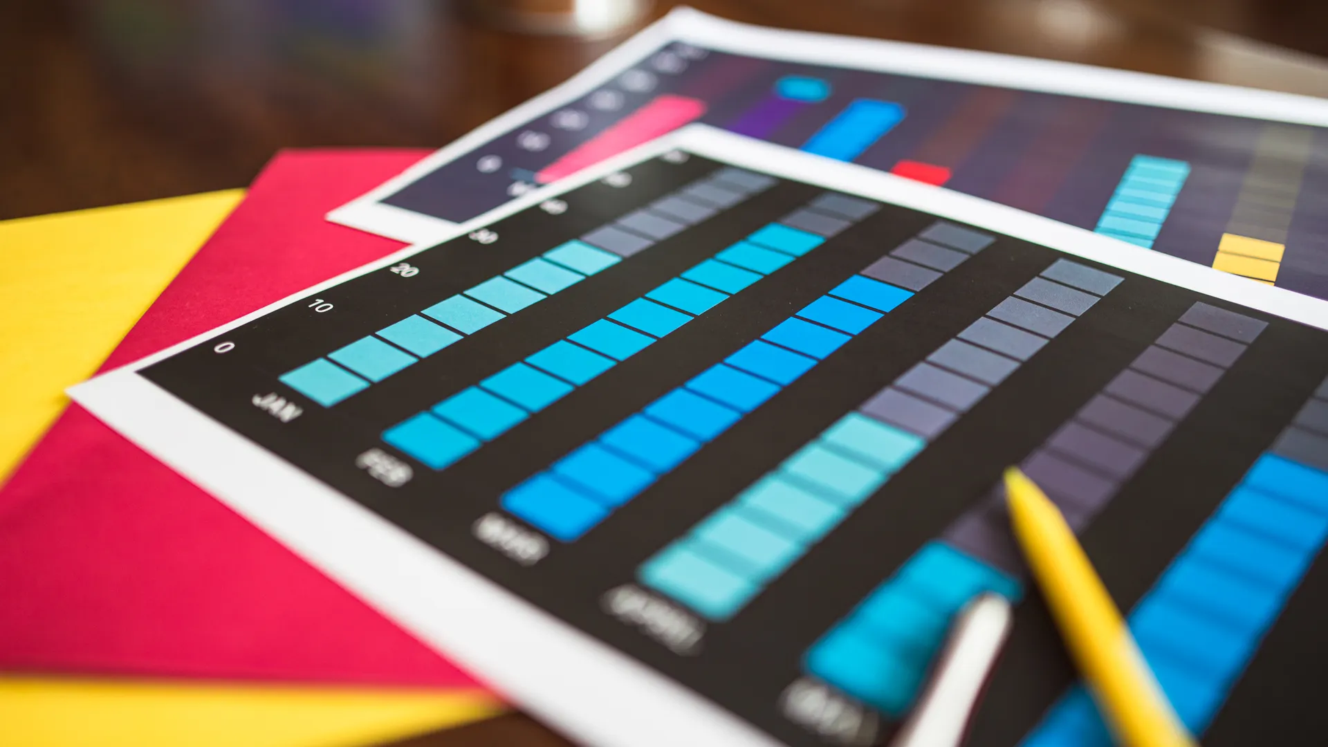 Close-up of colorful financial charts and a pencil on a wooden desk