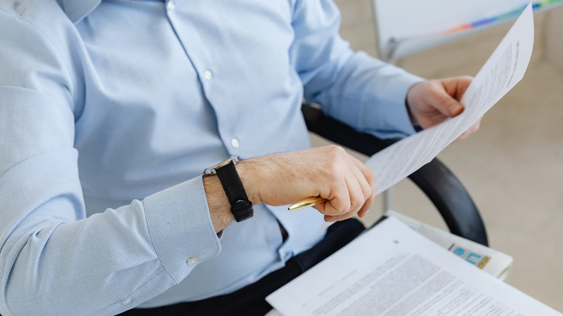 Businessman reviewing papers in office setting, highlighting analysis and attention to detail