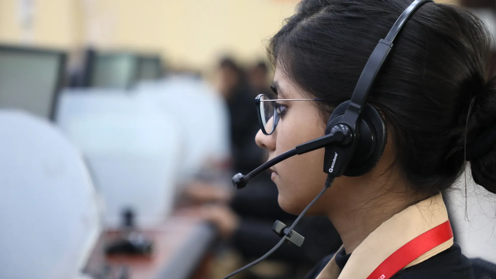 Side view of a woman working in a call center, wearing a headset and focused on her task