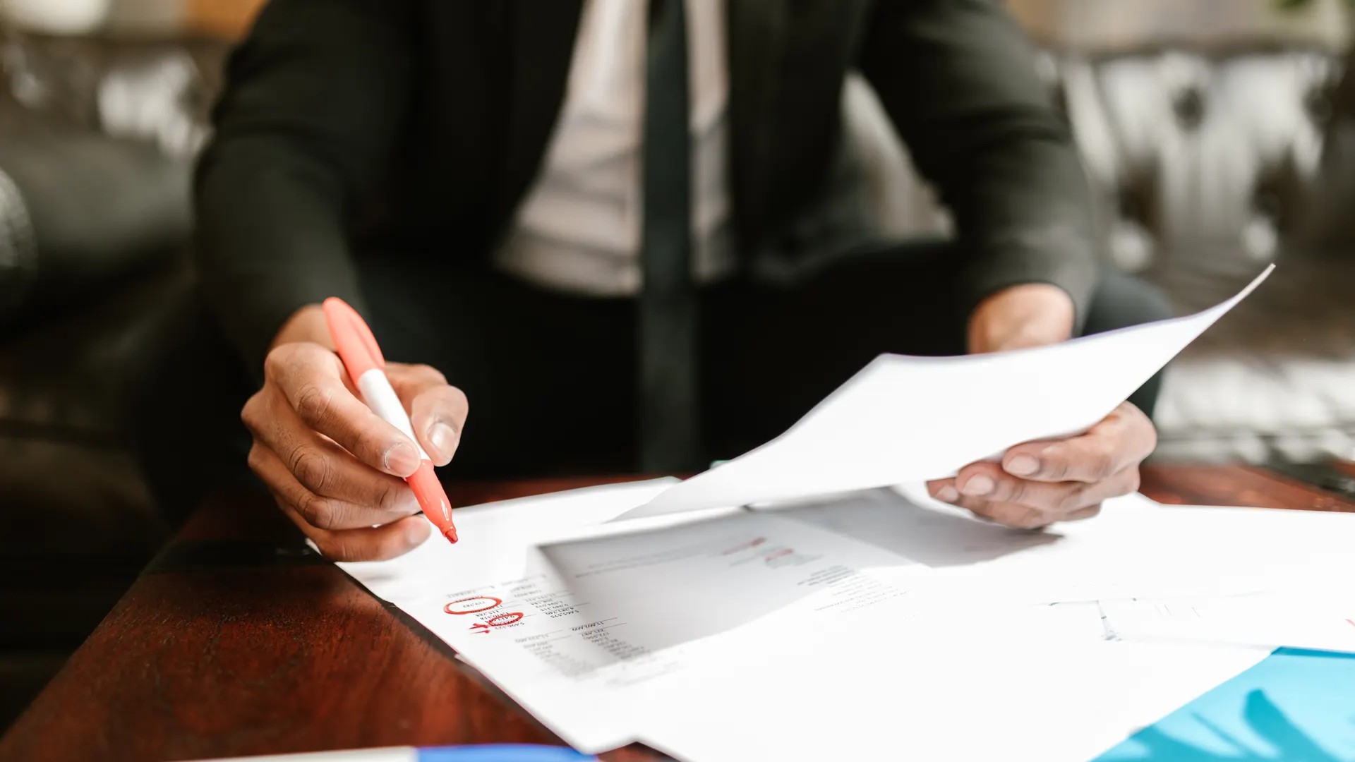Businessman working with financial documents at office desk, highlighting details