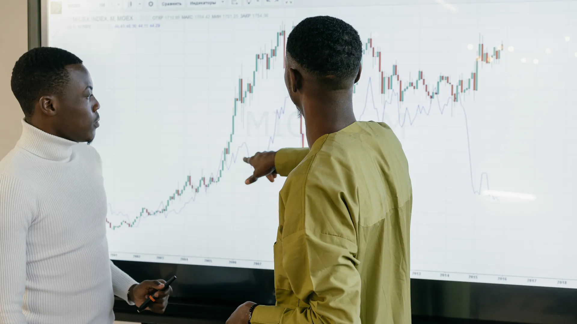 Two professionals discussing financial trends on a graph at the office