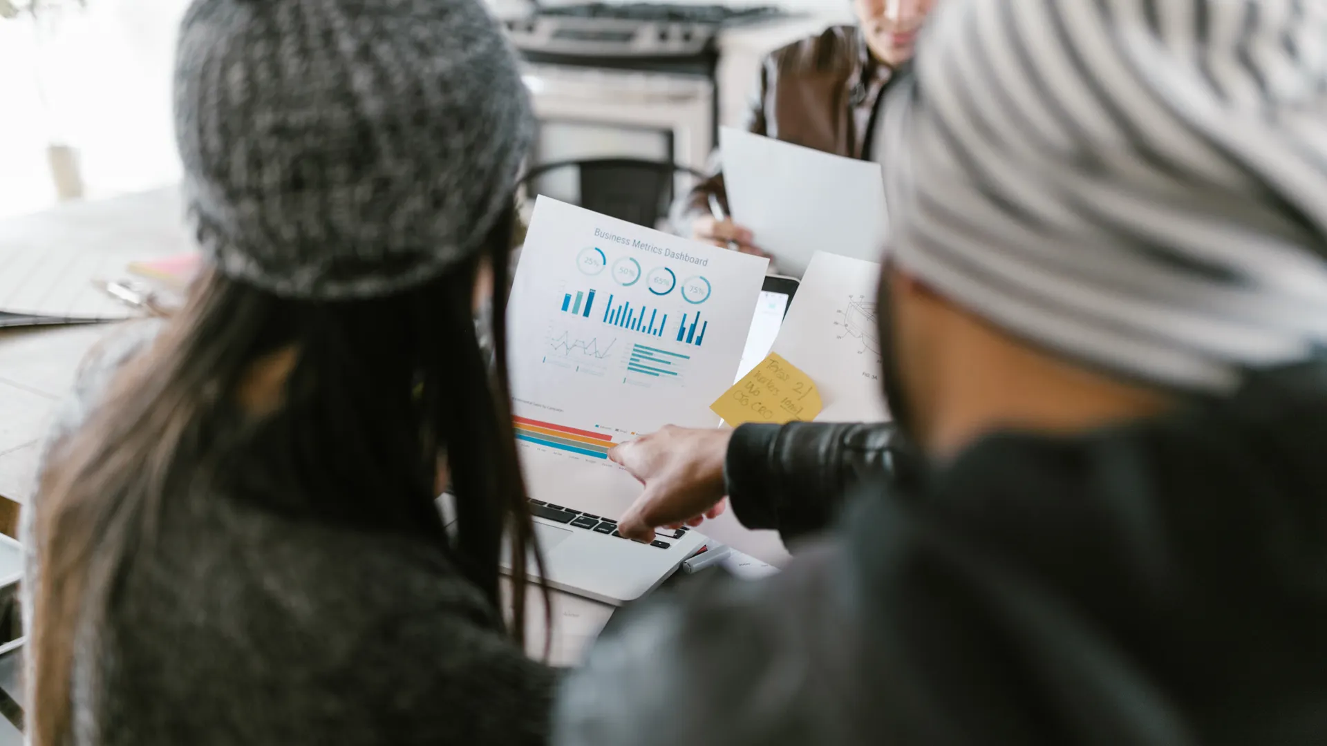 Team members discussing business metrics using printed charts in a cozy meeting space