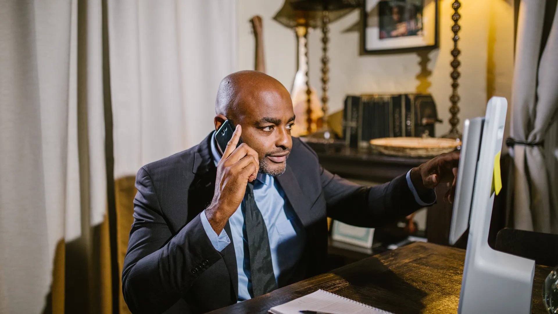 Professional adult man multitasking with phone and computer in an office setting
