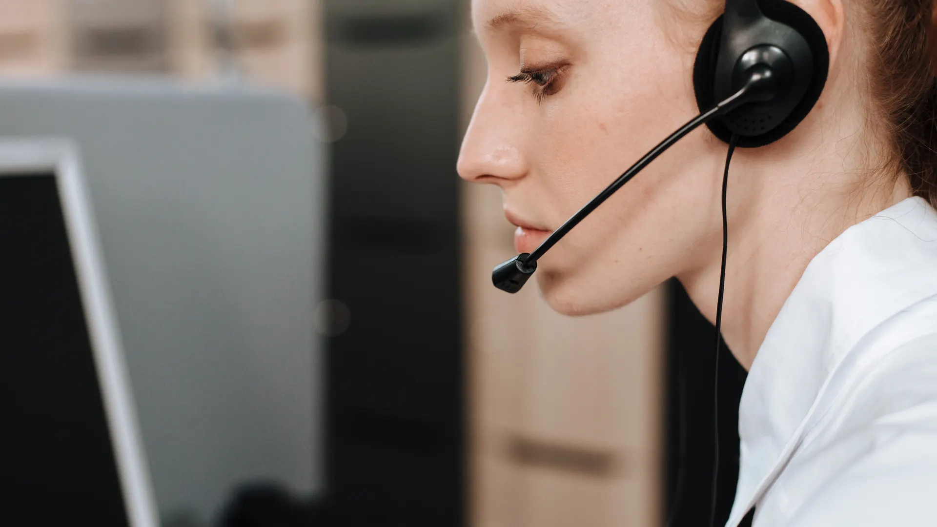 Close-up of a female call center agent using a headset while working at her desk