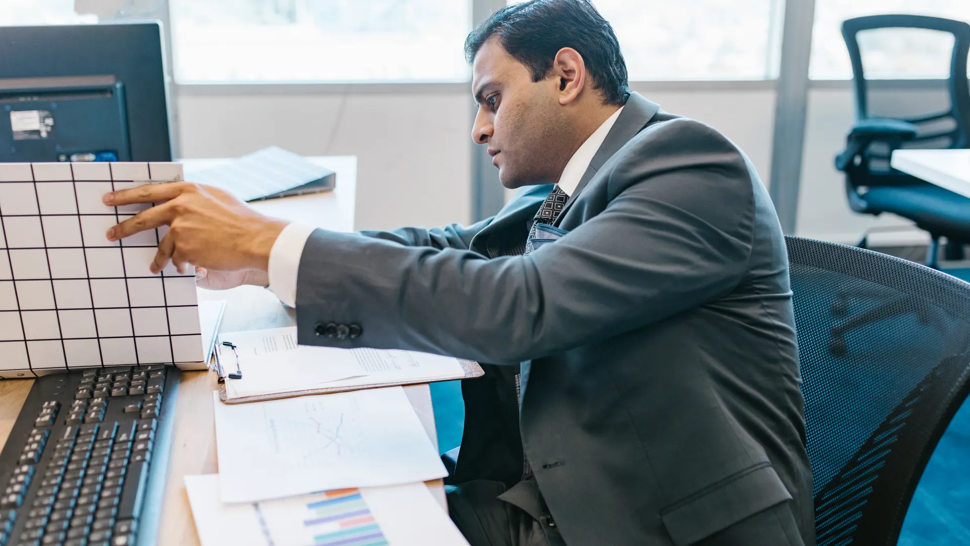 A businessman in a suit reviewing data charts at his office desk