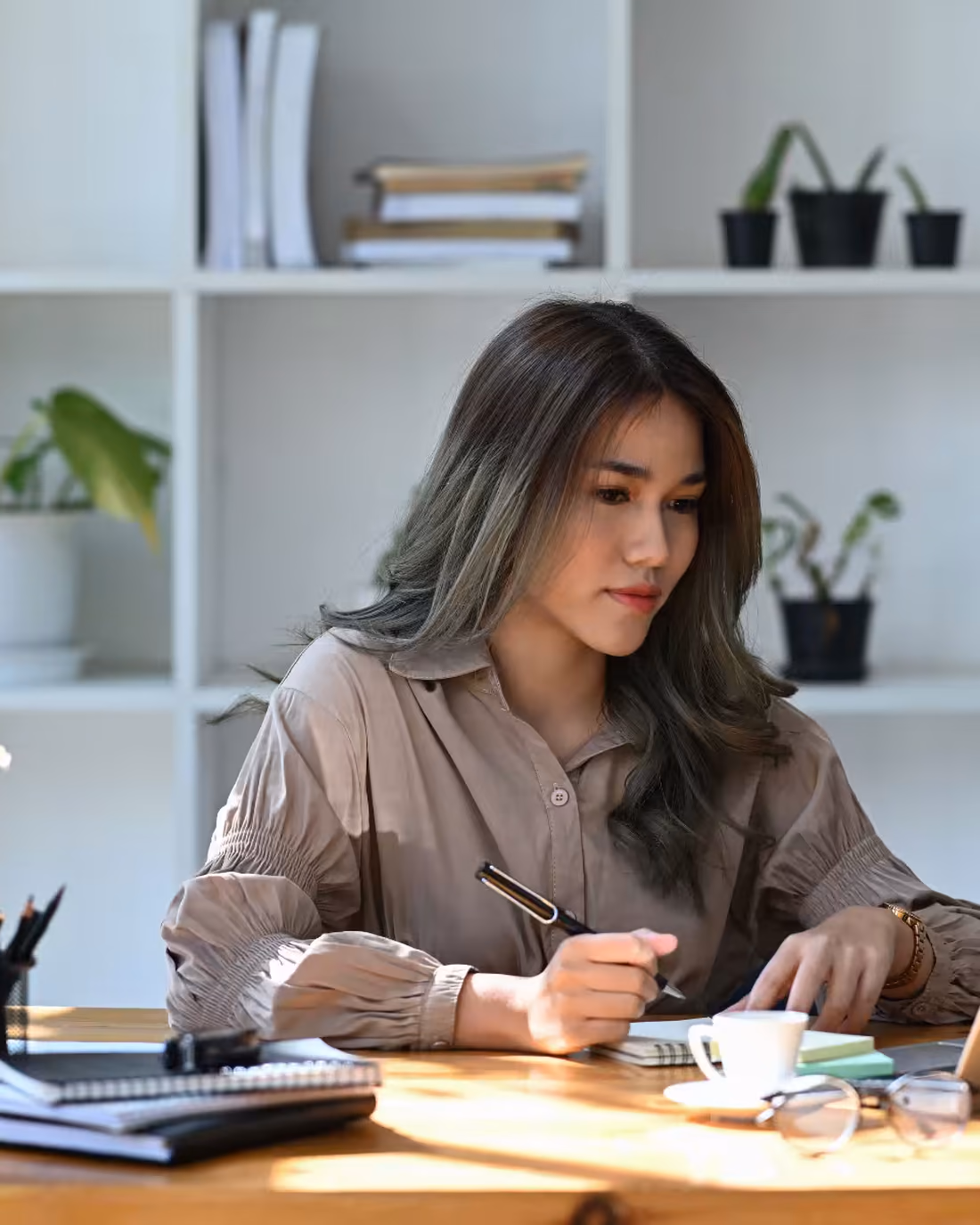 An analyst mapping out a process at her desk, notes and laptop in front of her