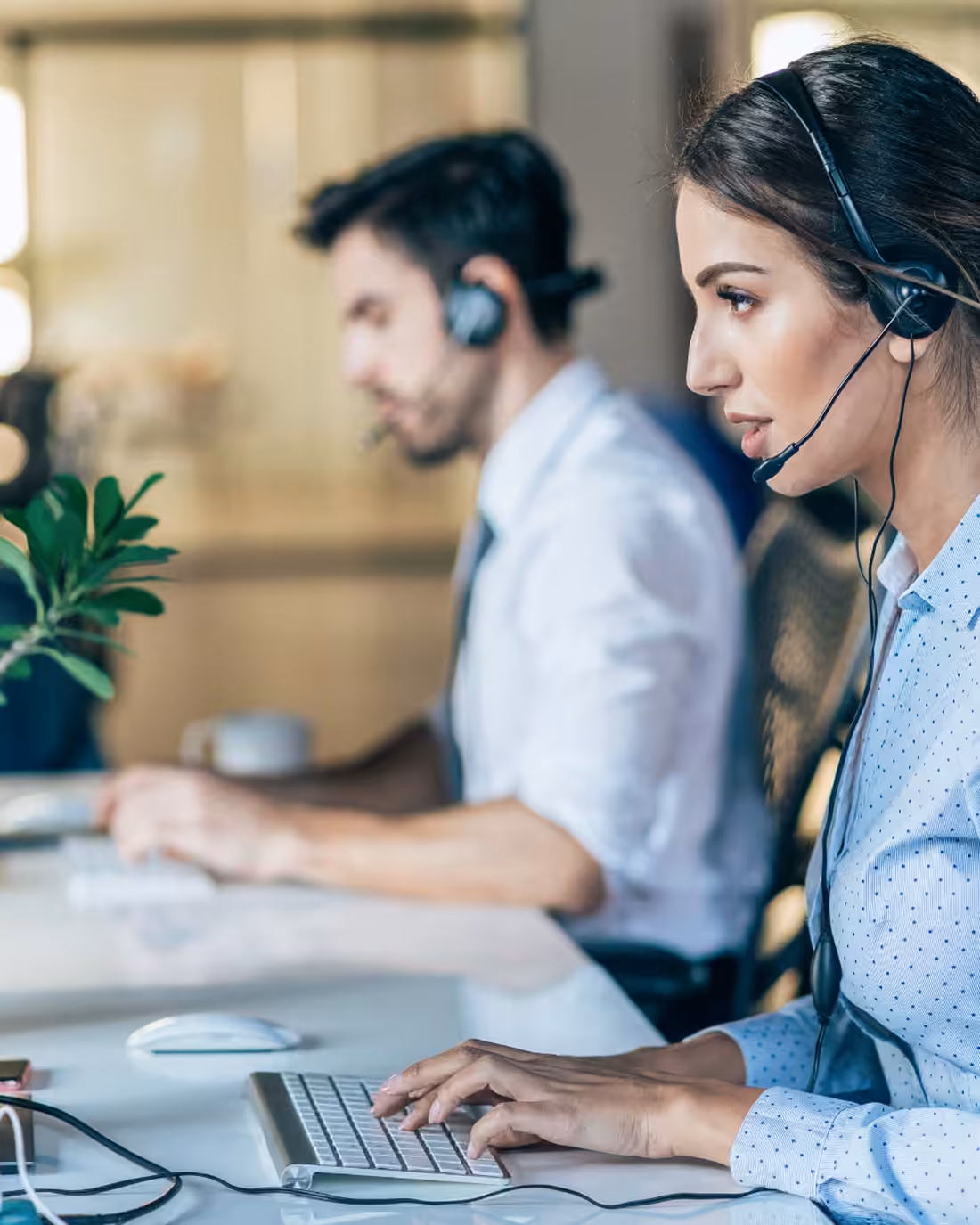 Two experience specialists working side by side at their monitors on the support floor