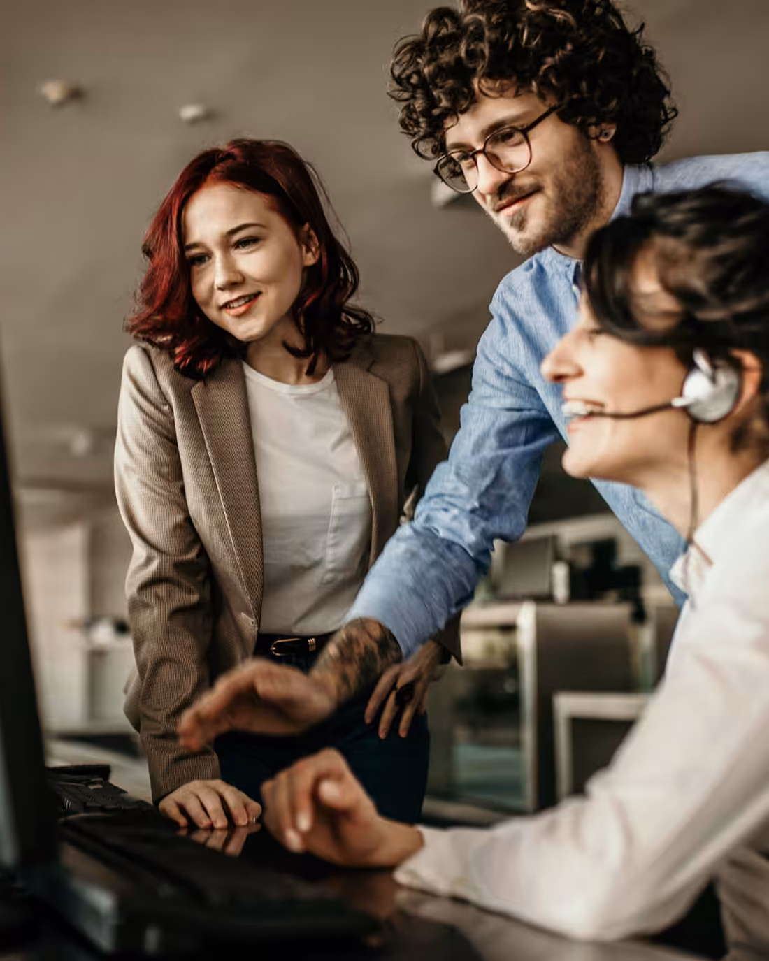 Three Abacus support colleagues reviewing a customer account together at a monitor, one of them on a headset