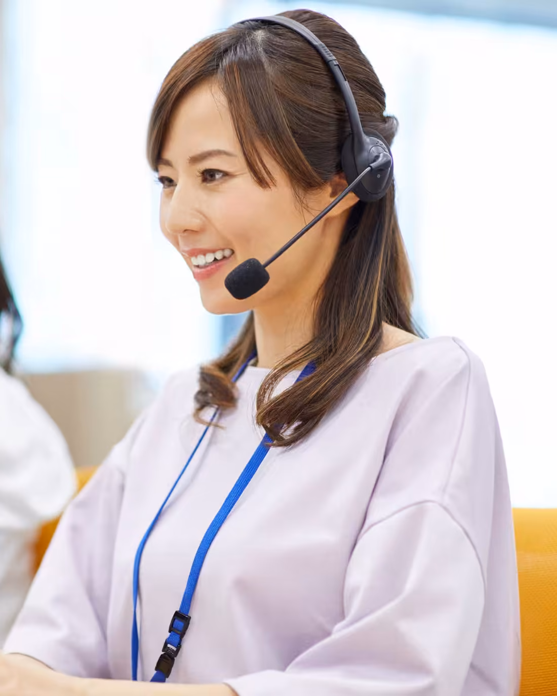 An outbound agent on a headset mid-call at her desk, a colleague working alongside her