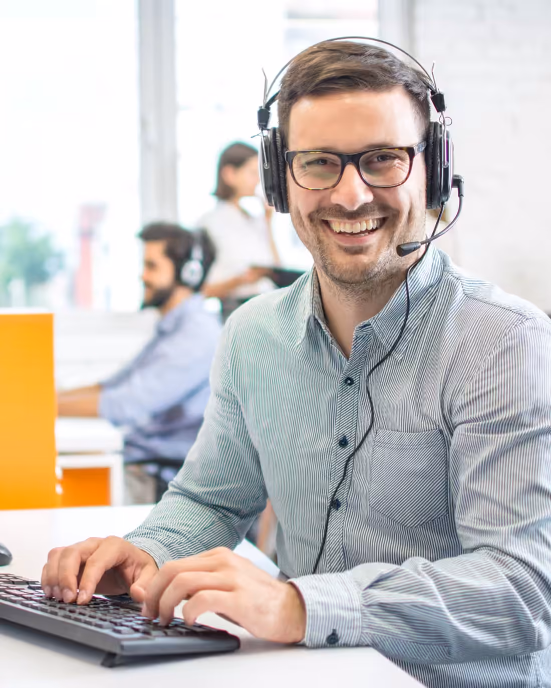 A sales support specialist on a headset updating CRM records between calls
